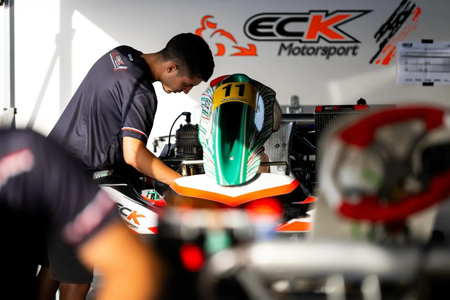 Mecánico de ECK trabajando en un kart bajo la carpa del equipo